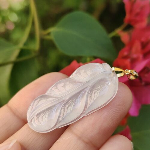 a hand holding a white leaf pendant