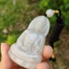 a hand holding a white buddha pendant