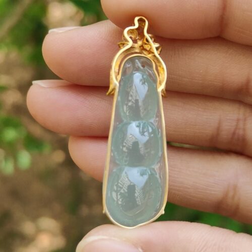 a hand holding a gold and blue pendant