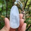 a hand holding a jade pendant