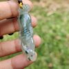 a hand holding a jade pendant