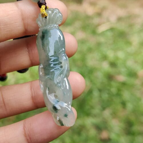 a hand holding a jade pendant