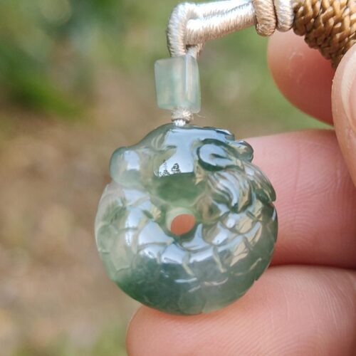 a hand holding a jade pendant