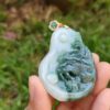 une main tenant un pendentif en jade