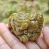 Una mano sosteniendo un pequeño animal de piedra verde.