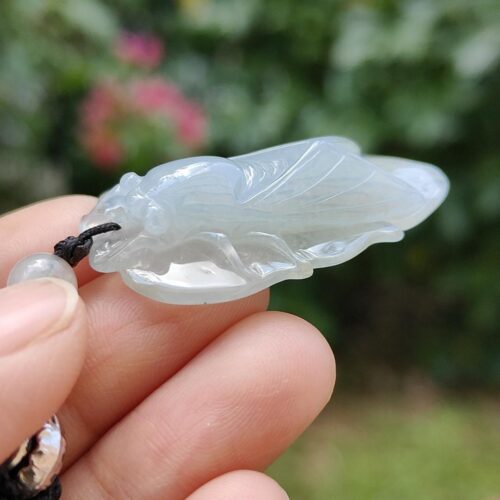 a hand holding a white bug pendant