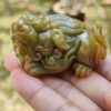 a hand holding a small green animal