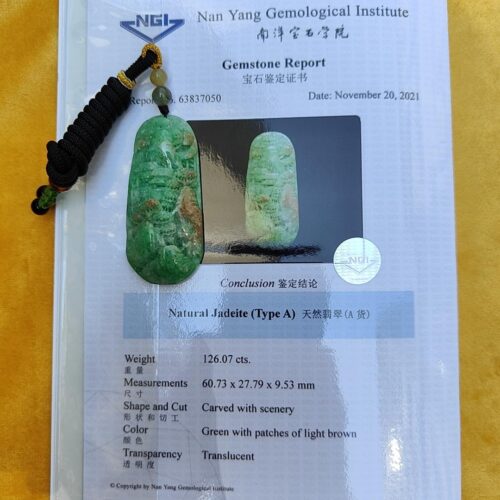 a green stone pendant on a piece of paper