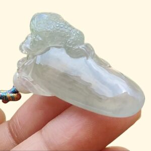 một bàn tay cầm một mặt dây chuyền ngọc bích