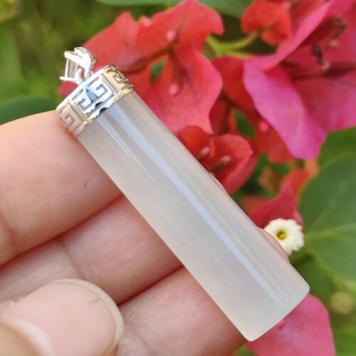 a hand holding a white jade pendant