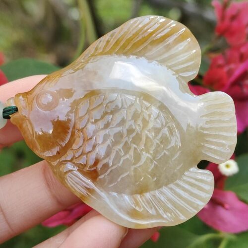 a hand holding a stone fish pendant