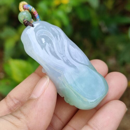 a hand holding a jade pendant