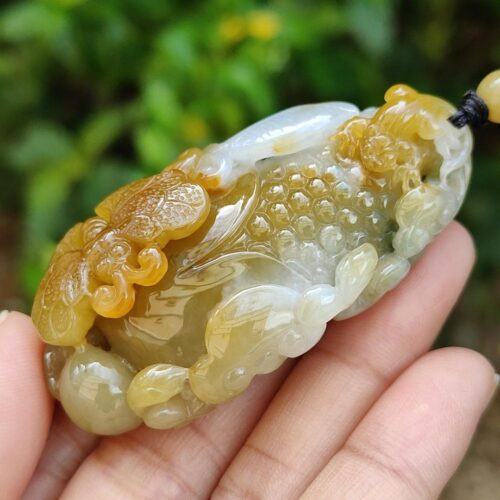 une main tenant un pendentif en jade