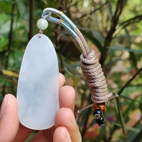 a hand holding a white stone pendant