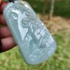 a hand holding a jade pendant