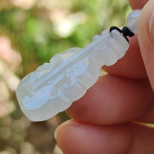 Una mano sosteniendo un colgante de jade blanco.