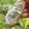 a hand holding a rock with a green and white rock