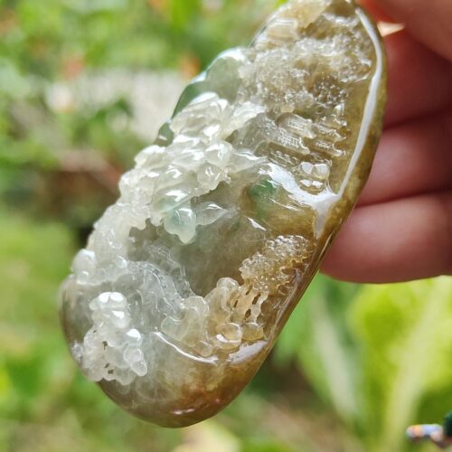 a hand holding a rock with a green and white rock