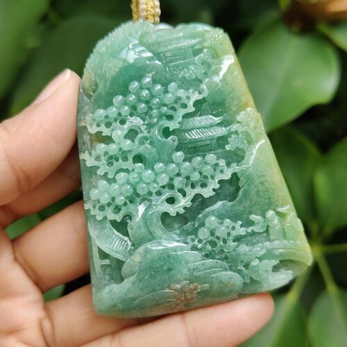 a hand holding a jade pendant