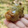 Una mano sosteniendo un pequeño animal de piedra verde.