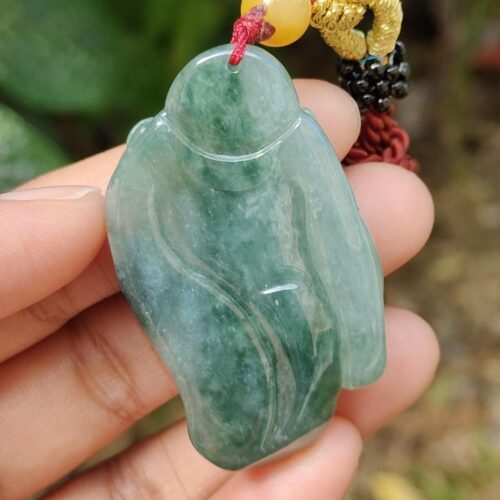 a hand holding a jade pendant