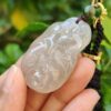 a hand holding a jade pendant