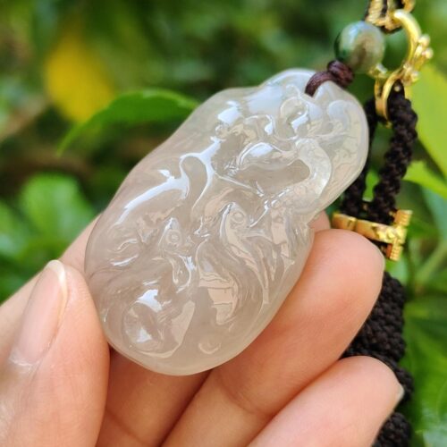 a hand holding a jade pendant