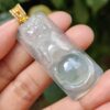 a hand holding a jade pendant