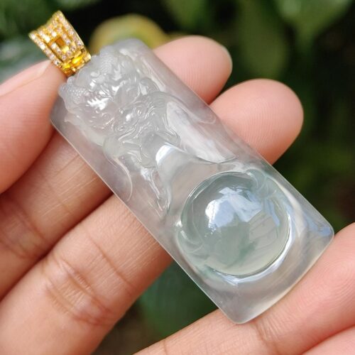 a hand holding a jade pendant