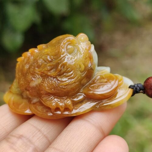 a hand holding a small frog shaped stone