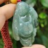 a hand holding a jade pendant