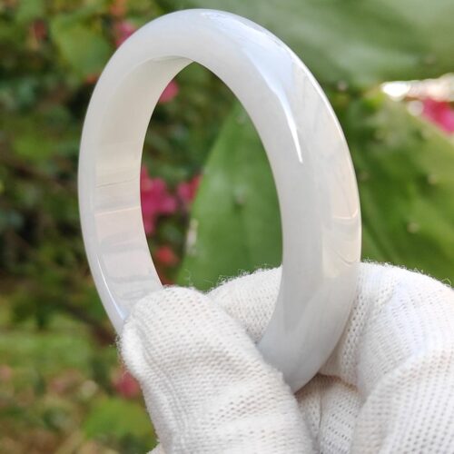 a hand in a glove holding a white ring