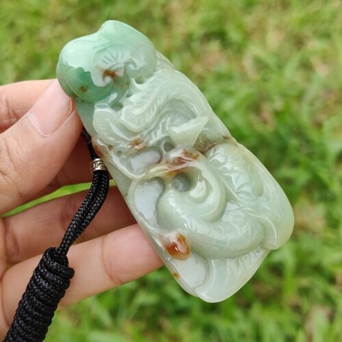 a hand holding a jade pendant