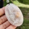 a hand holding a jade pendant