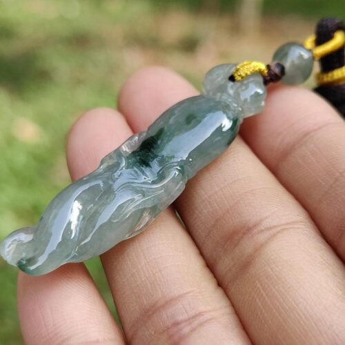 a hand holding a jade pendant