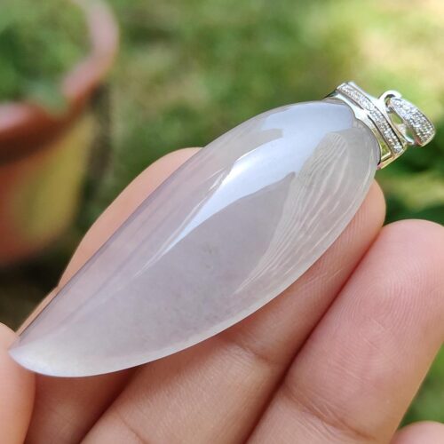 một bàn tay cầm một mặt dây chuyền đá trắng