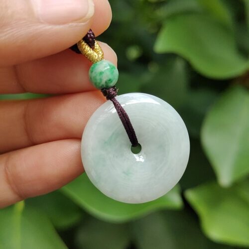 une main tenant un pendentif en jade