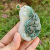 une main tenant un pendentif en jade