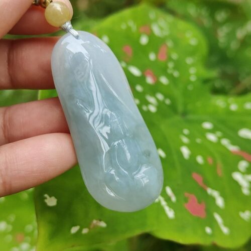 Una mano sosteniendo un colgante de jade azul.
