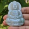 a person holding a jade buddha statue