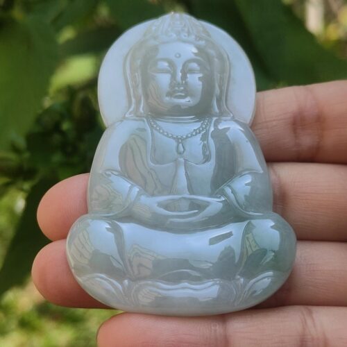 a person holding a jade buddha statue