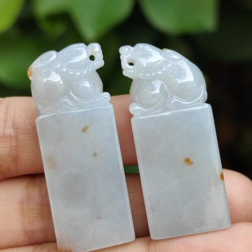 a hand holding a pair of jade carvings