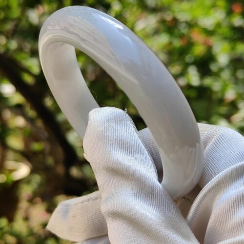 a hand in a glove holding a white ring