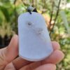 Una mano sosteniendo un colgante de jade.