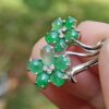 a hand holding a ring with green stones