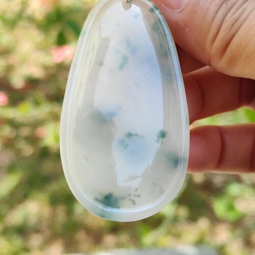 a hand holding a white and green pendant