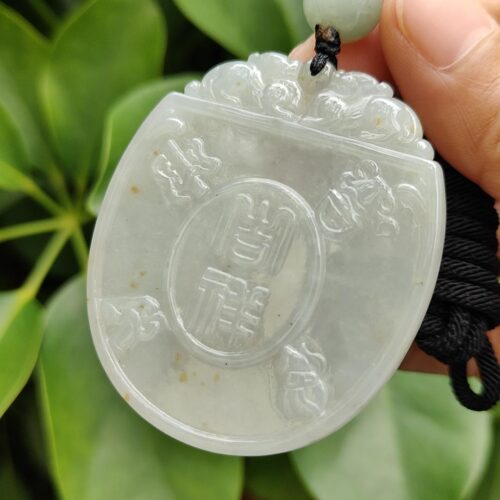 une main tenant un pendentif en jade