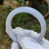 a hand in a glove holding a white ring