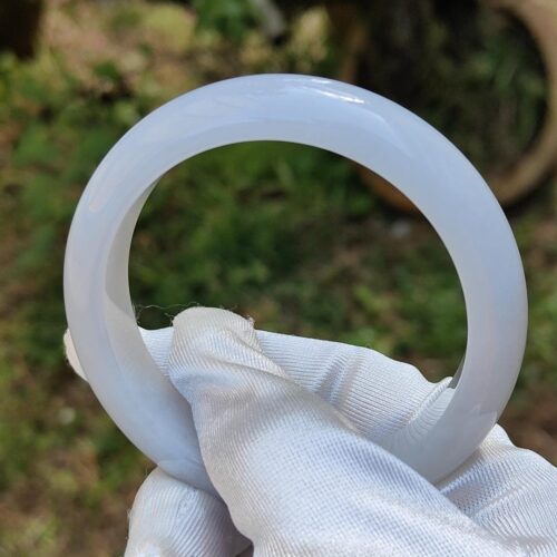 a hand in a glove holding a white ring