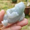 a hand holding a small jade frog